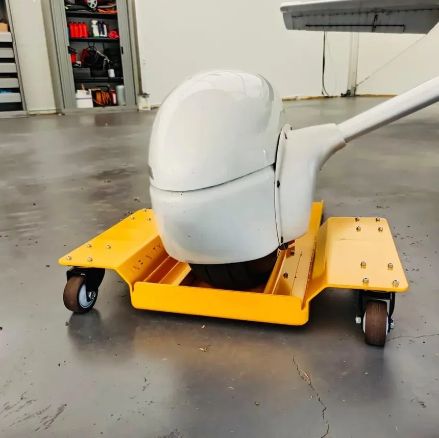 Yellow 360 degree aircraft wheel dolly positioned under an airplane nose wheel