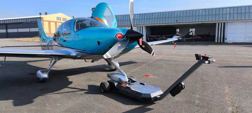 GRAVITY electric aircraft tug hooked to the nose wheel of a business jet inside a hangar